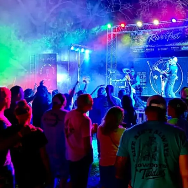 Crowd dancing under colored stage lights at an outdoor Jordan Beem festival show