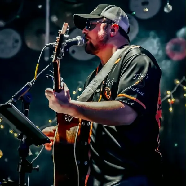 Jordan Beem singing with his acoustic guitar under string lights