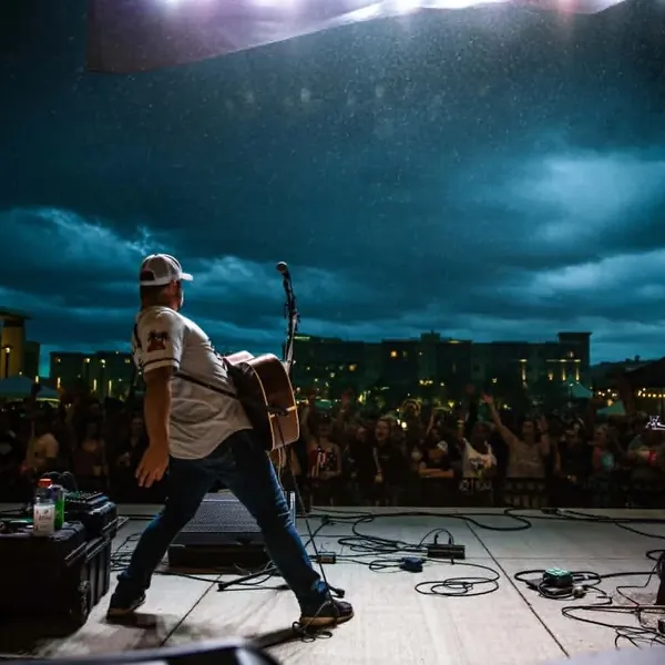 Jordan Beem crossing an outdoor stage in front of the crowd at dusk