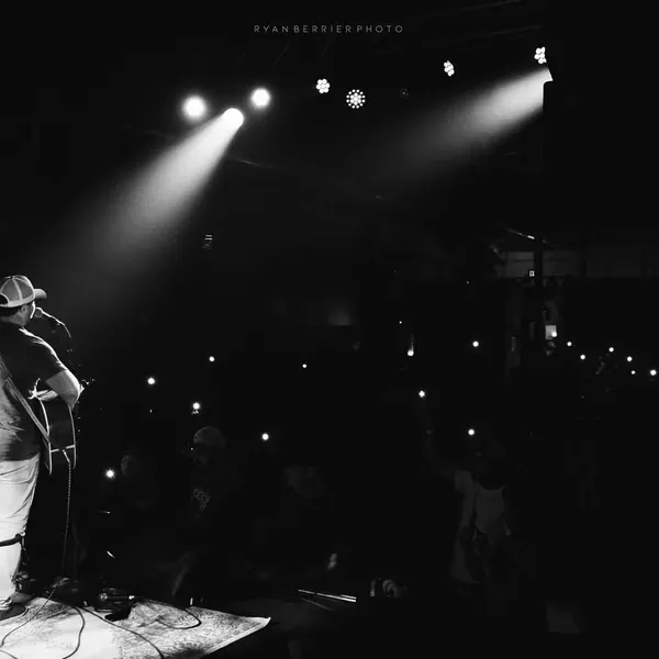 Black and white photo of stage lights over the crowd at a Jordan Beem concert