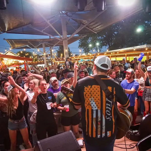 Jordan Beem performing for a packed outdoor bar crowd under a canopy